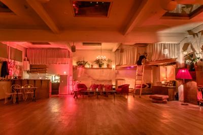 Salle spacieuse avec éclairage tamisé orange, murs en pierre, bancs en bois et décorations végétales.