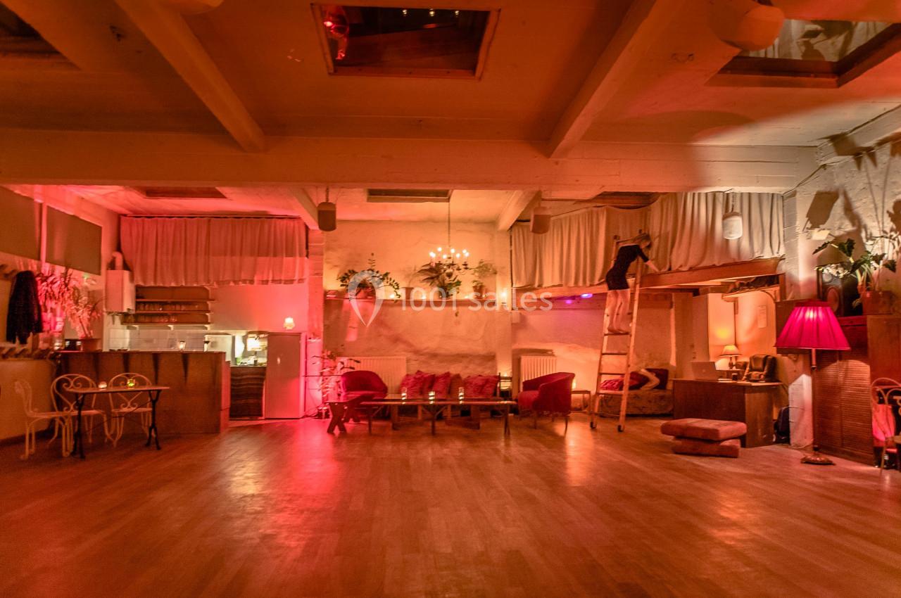 Salle chaleureuse avec éclairage tamisé, meubles en bois, coussins, plantes et une échelle près d'une mezzanine.