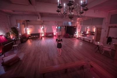 Salle spacieuse avec éclairage tamisé orange, murs en pierre, bancs en bois et décorations végétales.