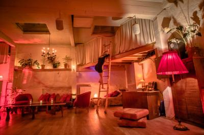 Salle spacieuse avec éclairage tamisé orange, murs en pierre, bancs en bois et décorations végétales.