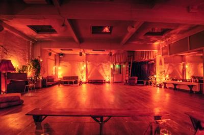 Salle spacieuse avec éclairage tamisé orange, murs en pierre, bancs en bois et décorations végétales.