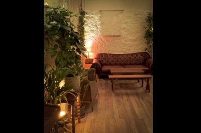 Salle spacieuse avec éclairage tamisé orange, murs en pierre, bancs en bois et décorations végétales.