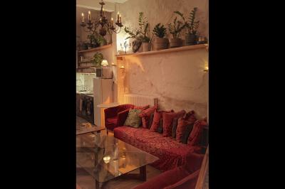 Salle spacieuse avec éclairage tamisé orange, murs en pierre, bancs en bois et décorations végétales.