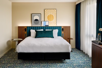 Salle de bain moderne avec baignoire, paroi vitrée, lavabo avec miroir éclairé et étagère contenant des serviettes.
