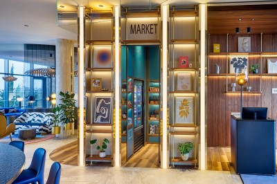 Salle de bain moderne avec baignoire, paroi vitrée, lavabo avec miroir éclairé et étagère contenant des serviettes.