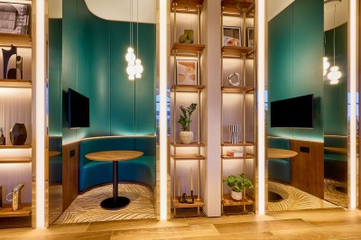 Salle de bain moderne avec baignoire, paroi vitrée, lavabo avec miroir éclairé et étagère contenant des serviettes.