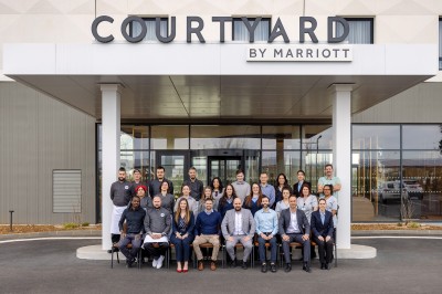 Salle de bain moderne avec baignoire, paroi vitrée, lavabo avec miroir éclairé et étagère contenant des serviettes.