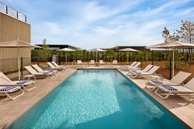 Salle de bain moderne avec baignoire, paroi vitrée, lavabo avec miroir éclairé et étagère contenant des serviettes.