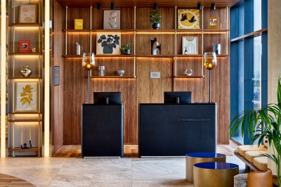 Salle de bain moderne avec baignoire, paroi vitrée, lavabo avec miroir éclairé et étagère contenant des serviettes.