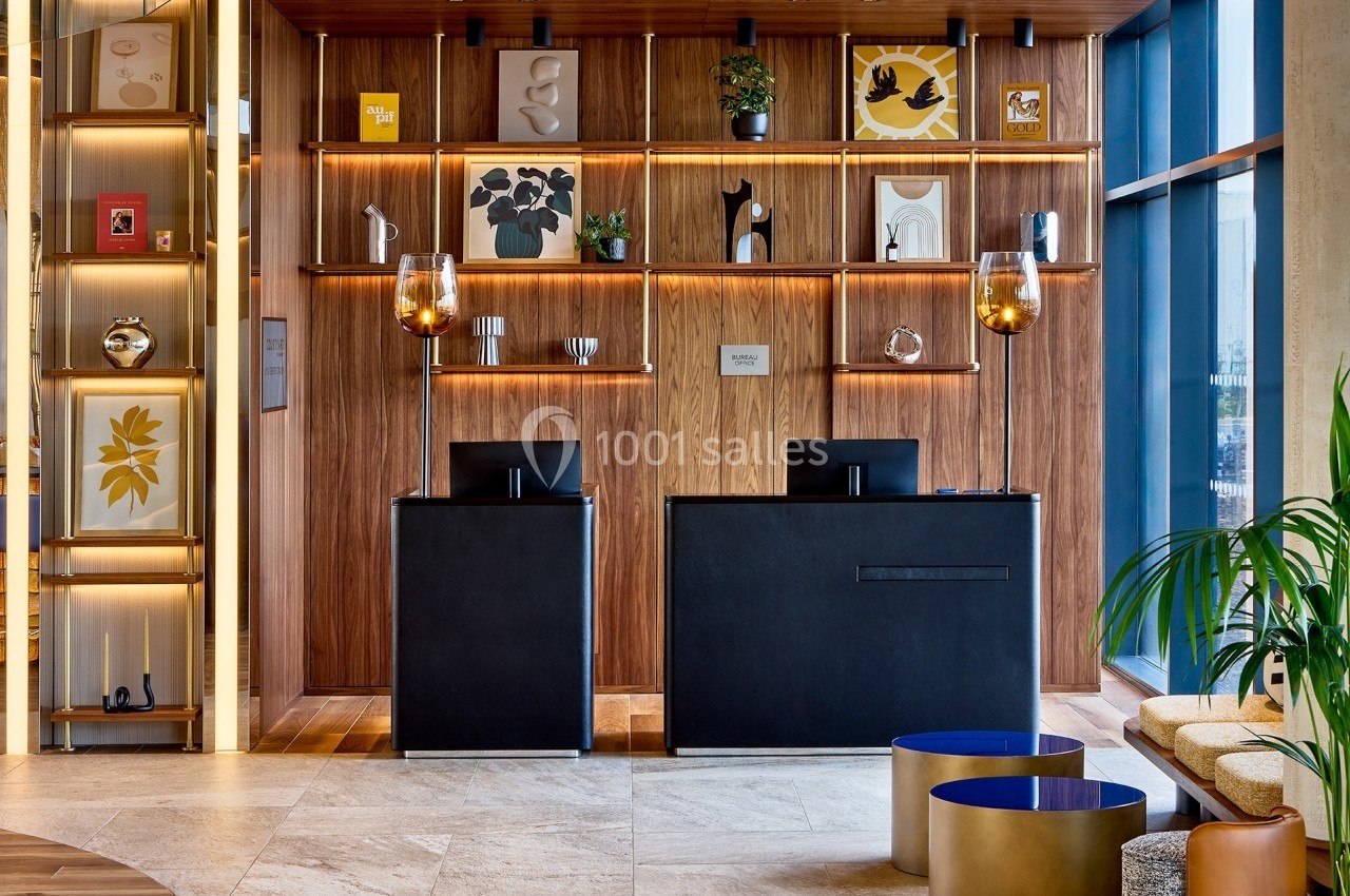 Comptoirs d'accueil modernes devant un mur en bois décoré d'étagères avec des objets et des cadres artistiques.