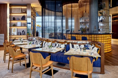 Salle de bain moderne avec baignoire, paroi vitrée, lavabo avec miroir éclairé et étagère contenant des serviettes.