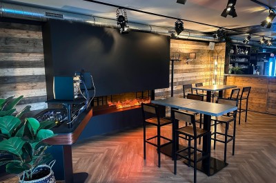 Vue d'un intérieur avec un espace ouvert, un bar en briques, un parquet clair et une mezzanine avec rambarde blanche.