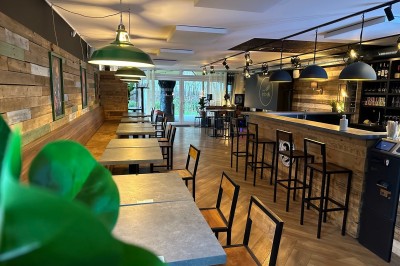 Vue d'un intérieur avec un espace ouvert, un bar en briques, un parquet clair et une mezzanine avec rambarde blanche.