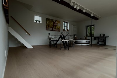 Vue d'un intérieur avec un espace ouvert, un bar en briques, un parquet clair et une mezzanine avec rambarde blanche.