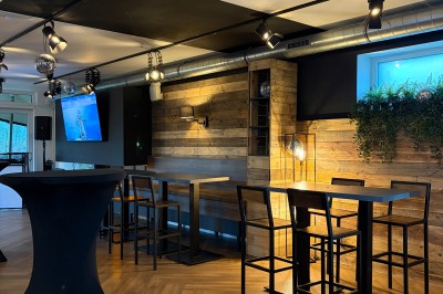 Vue d'un intérieur avec un espace ouvert, un bar en briques, un parquet clair et une mezzanine avec rambarde blanche.