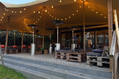 Vue d'un intérieur avec un espace ouvert, un bar en briques, un parquet clair et une mezzanine avec rambarde blanche.