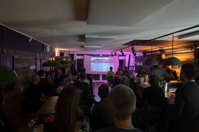 Camion de restauration éclairé la nuit, stationné devant un bâtiment illuminé par une lumière bleue.