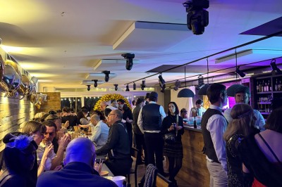 Camion de restauration éclairé la nuit, stationné devant un bâtiment illuminé par une lumière bleue.