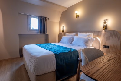 Une main verse un cocktail rose dans un verre décoré d'une tranche de citron vert, avec des boissons et snacks en arrière…