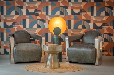 Une main verse un cocktail rose dans un verre décoré d'une tranche de citron vert, avec des boissons et snacks en arrière…