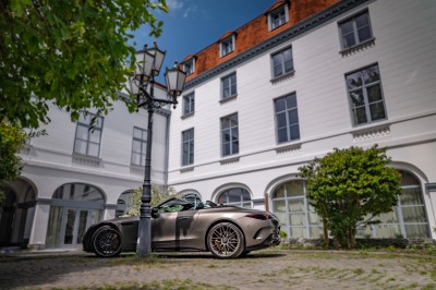 Une main verse un cocktail rose dans un verre décoré d'une tranche de citron vert, avec des boissons et snacks en arrière…