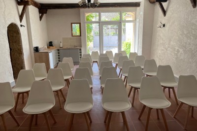 Porte-fenêtre vitrée blanche encadrée de pierre, avec une plante grimpante et une jardinière en pierre à droite.