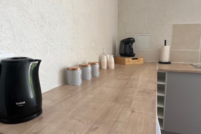 Porte-fenêtre vitrée blanche encadrée de pierre, avec une plante grimpante et une jardinière en pierre à droite.