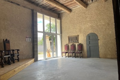 Porte-fenêtre vitrée blanche encadrée de pierre, avec une plante grimpante et une jardinière en pierre à droite.