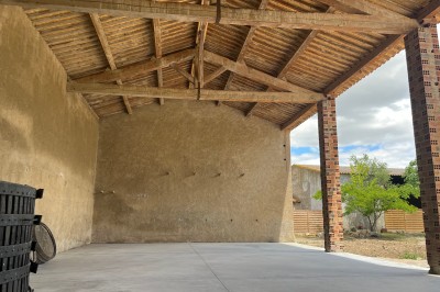 Porte-fenêtre vitrée blanche encadrée de pierre, avec une plante grimpante et une jardinière en pierre à droite.