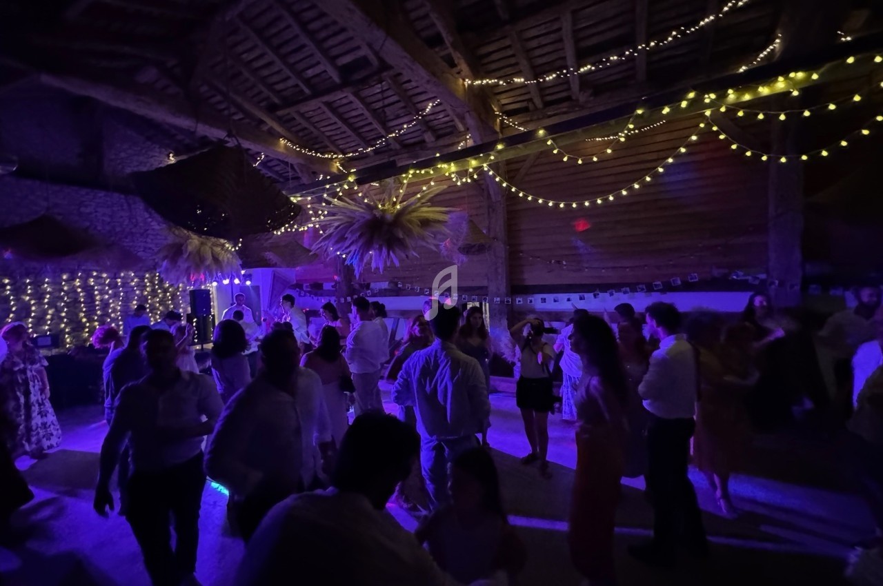 Personnes dansant sous des guirlandes lumineuses dans une salle avec un éclairage tamisé et une ambiance festive.