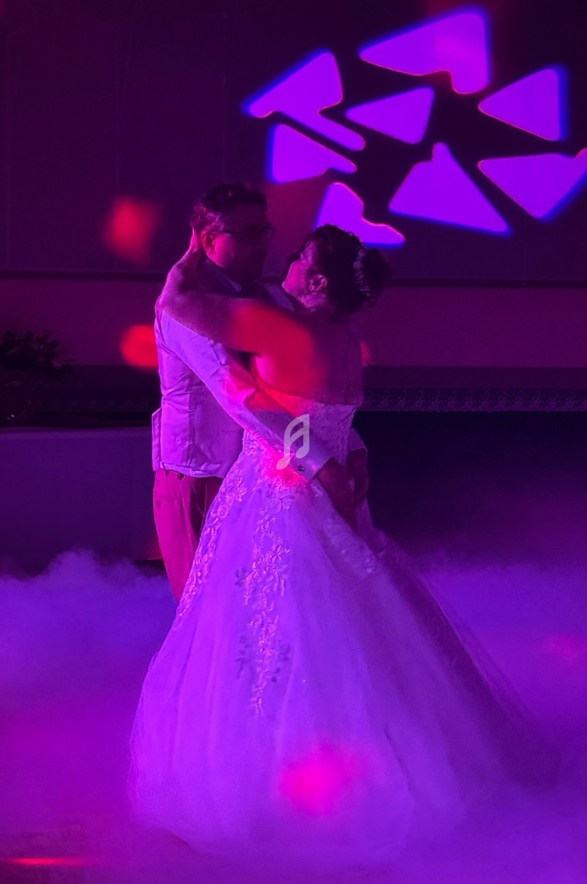 Un couple danse dans une ambiance lumineuse violette, entouré de fumée au sol.