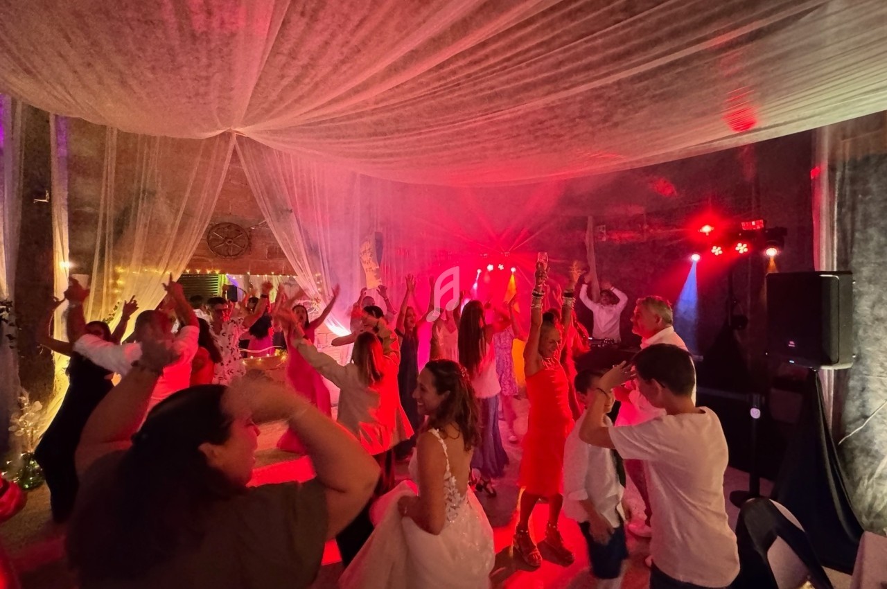 Personnes dansant sous des lumières rouges dans une salle décorée de voilages translucides.
