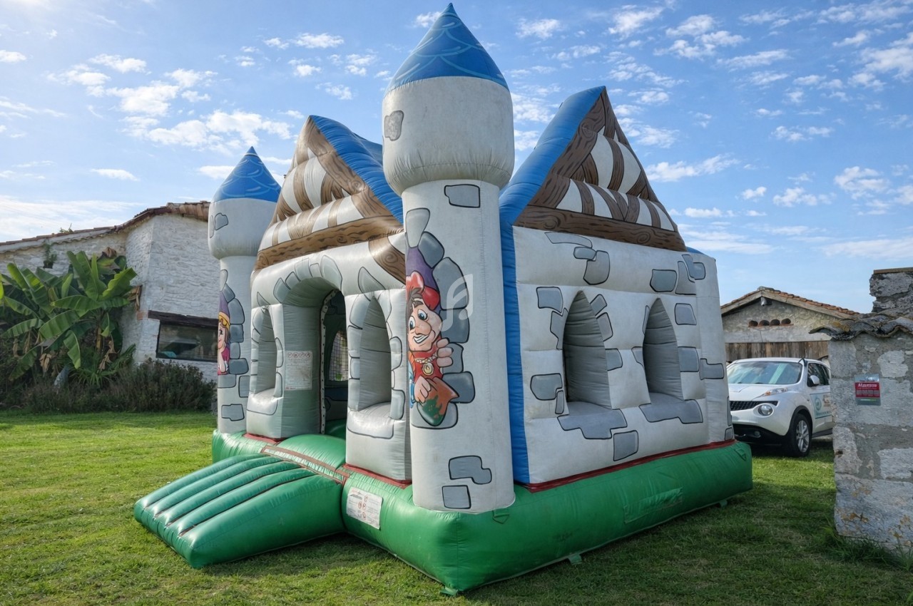 Château gonflable coloré en forme de forteresse médiévale installé sur une pelouse par temps ensoleillé.