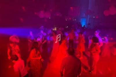 Personnes dansant dans une salle faiblement éclairée avec des lumières rouges et bleues, ambiance festive.