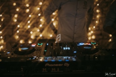 Console de mixage DJ éclairée, avec des lumières floues en arrière-plan dans une ambiance tamisée.