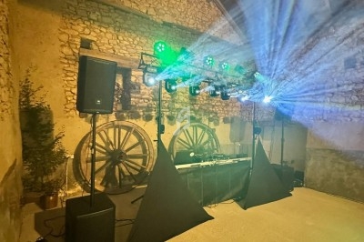 Installation de matériel de sonorisation et d'éclairage dans une salle en pierre avec des roues en bois décoratives.