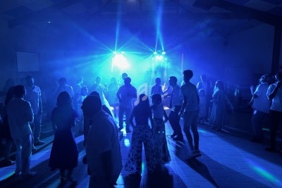 Groupe de personnes dansant sous des lumières bleues dans une salle sombre.
