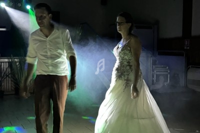 Un couple danse dans une salle faiblement éclairée avec des jeux de lumière et de la fumée.
