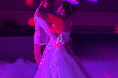 Un couple danse dans une ambiance lumineuse violette, entouré de fumée et de motifs lumineux en arrière-plan.