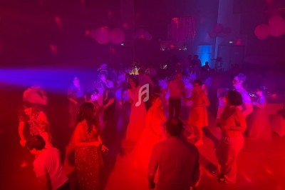 Personnes dansant dans une salle faiblement éclairée avec des lumières rouges et bleues, décorée pour une fête.