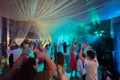 Des personnes dansent sous une tente éclairée par des lumières colorées lors d'une fête ou d'un événement.