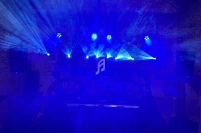Jeux de lumières bleues projetés dans une salle sombre avec des enceintes et des éléments de décoration en arrière-plan.