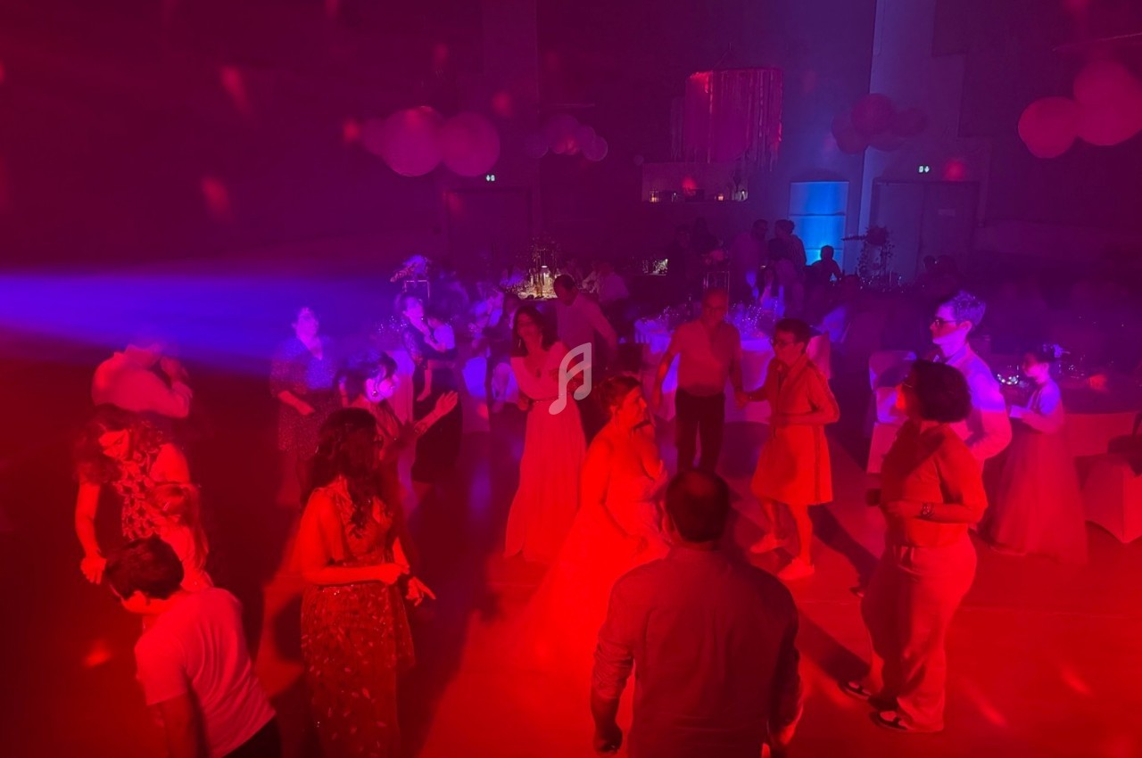 Personnes dansant dans une salle faiblement éclairée avec des lumières rouges et bleues, ambiance festive.