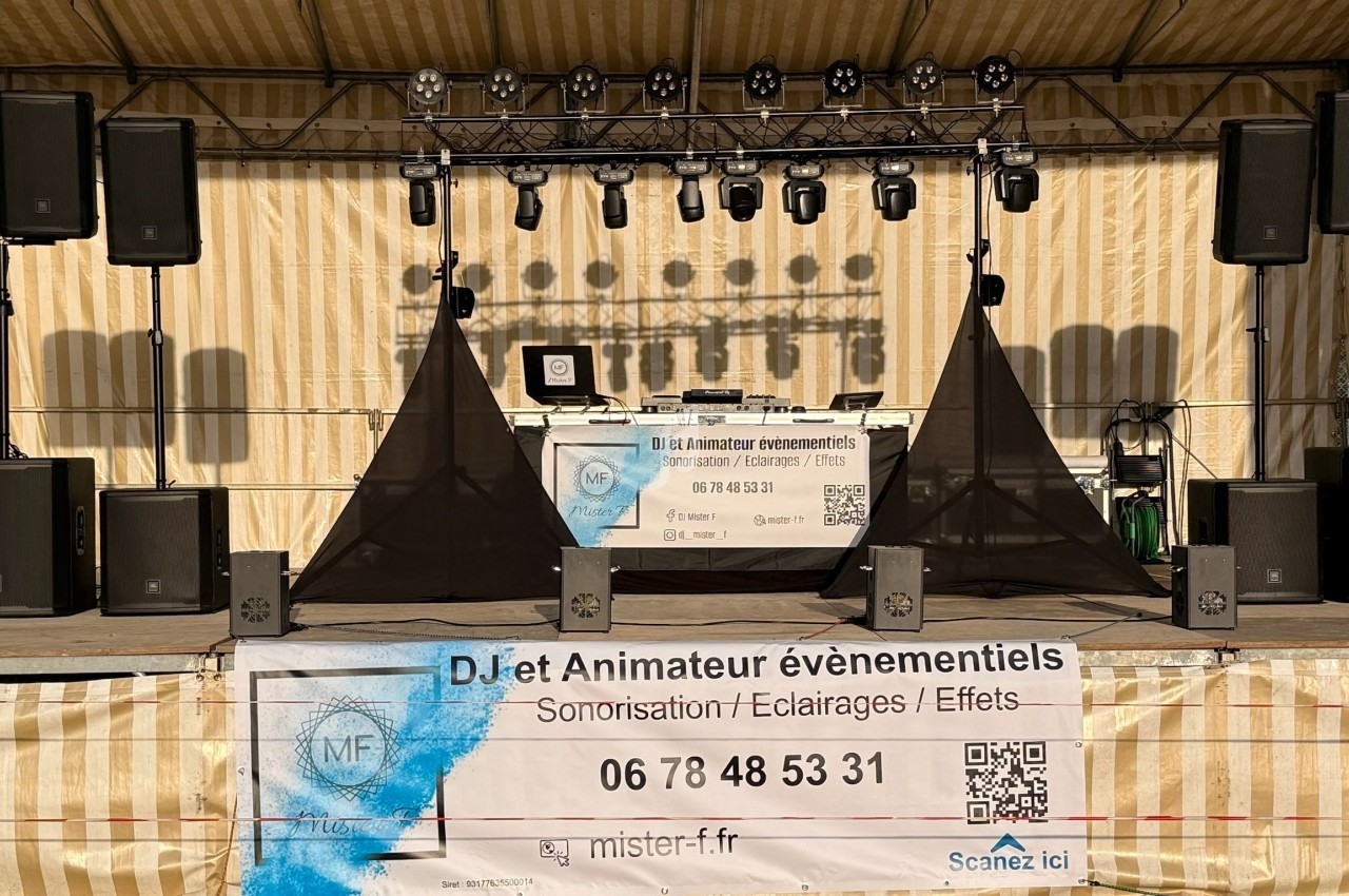 Installation de matériel de sonorisation et éclairage sur une scène extérieure avec une bannière publicitaire au premier…