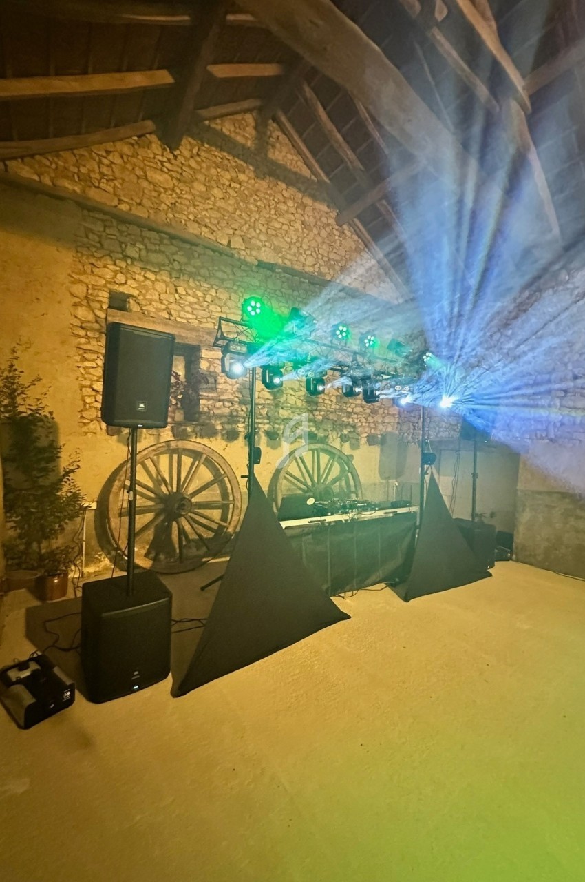 Installation de matériel de sonorisation et d'éclairage dans une salle en pierre avec des roues en bois décoratives.