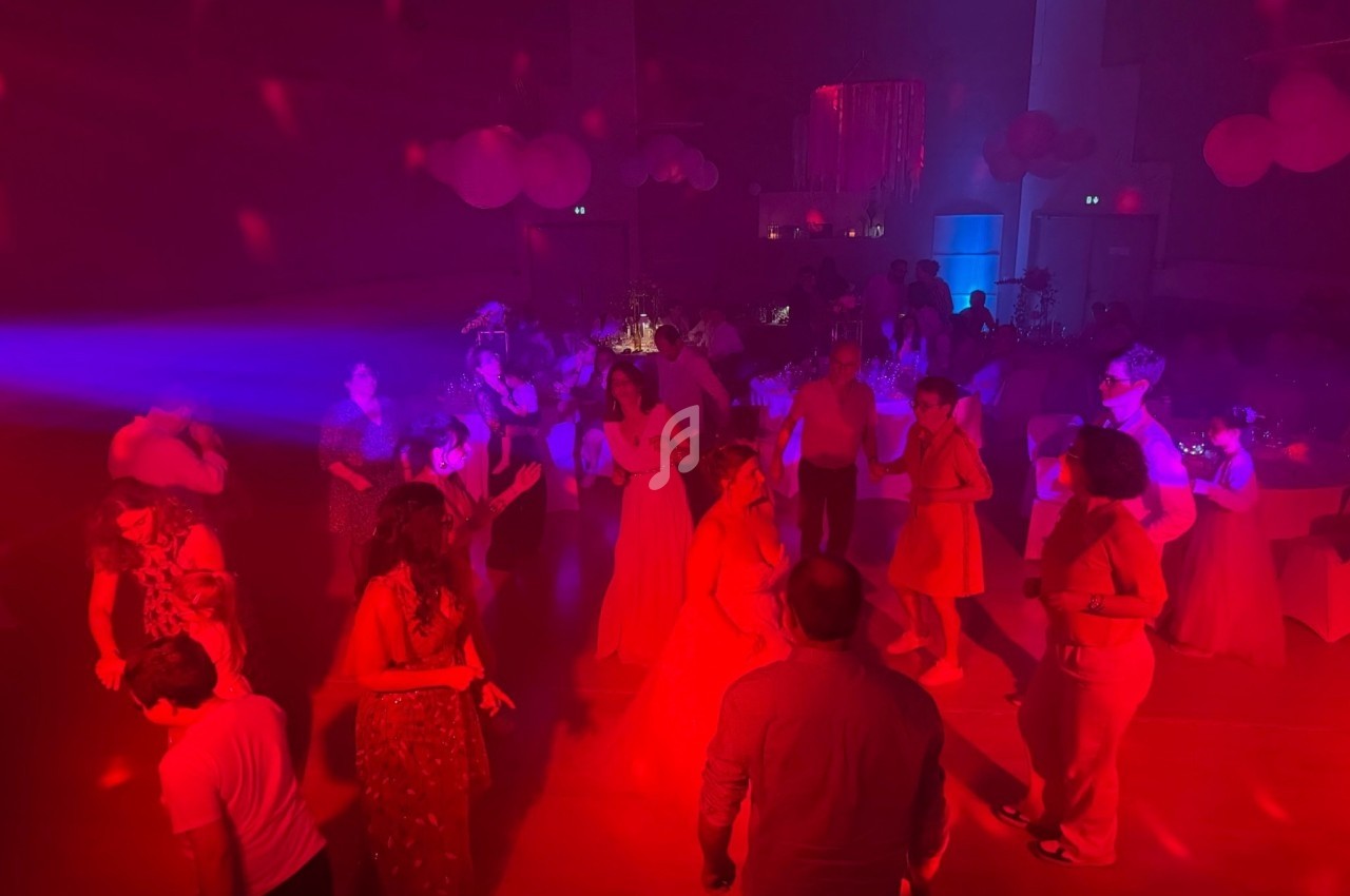 Personnes dansant dans une salle faiblement éclairée avec des lumières rouges et bleues, décorée pour une fête.
