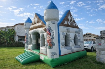 Structure gonflable colorée avec toboggans multiples installée sur une pelouse par une journée ensoleillée.