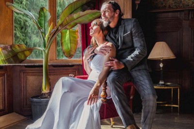 Bâtiment moderne en bois noir avec toit en pente, entouré d'arbres et d'un sol couvert de feuilles d'automne.