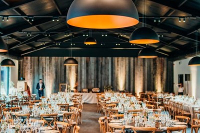 Bâtiment moderne en bois noir avec toit en pente, entouré d'arbres et d'un sol couvert de feuilles d'automne.