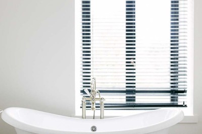 Bâtiment moderne en bois noir avec toit en pente, entouré d'arbres et d'un sol couvert de feuilles d'automne.